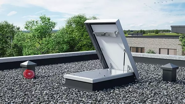 Columbus trapdoor on flat gravel roof with a view of trees and blue sky   