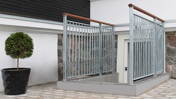 Nordic banister in galvanized steel with wooden handrail in front of basement entryway   